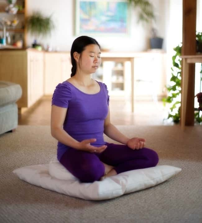 Young woman meditating in her living room