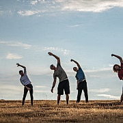 Group of people doing energization exercises on a golden field
