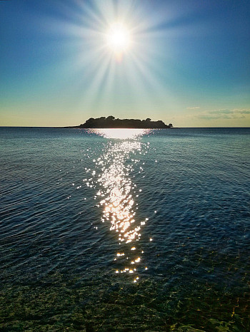 Sunrise Island, Pixabay - Blue sky and ocean with sun glistening over an island in the distance.