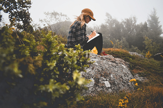 Woman sitting on a rock Journaling in nature